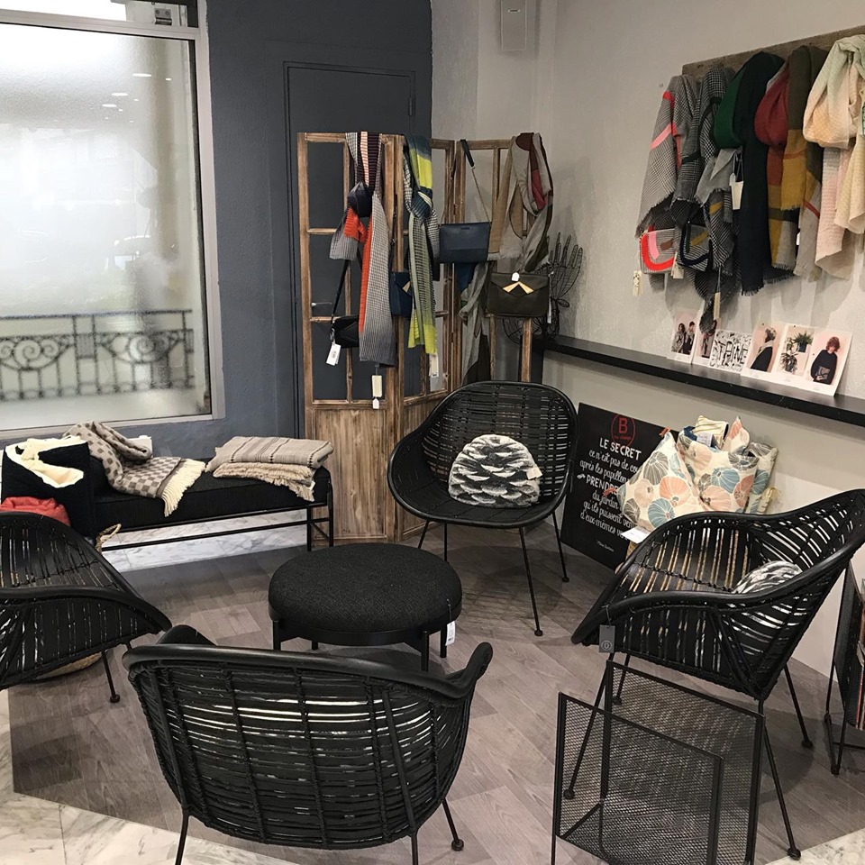Le coin salon : fauteuils noirs en rotin, et au mur les foulards et accessoires d'artisans proposés au salon.